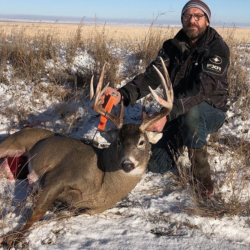 A hunter holding up the antlers of his deer kill.